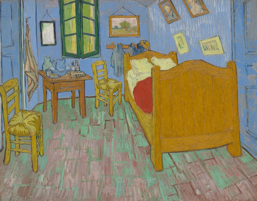 A painted bedroom with blue walls, a green-framed window, a wooden bed with a red cover, two yellow chairs, a small table and framed pictures.